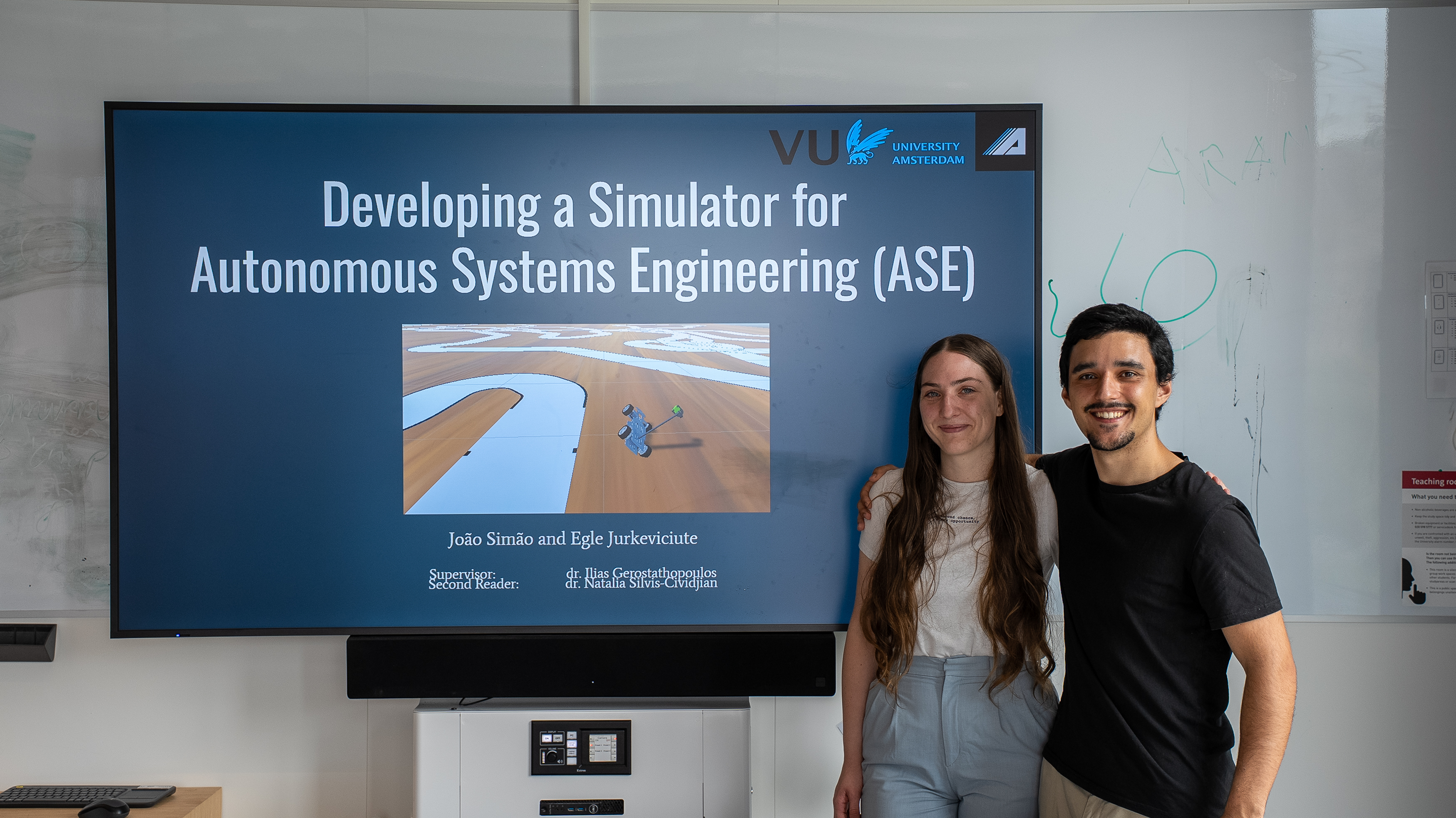 Egle and Simao standing in-front of title slide presentation picture